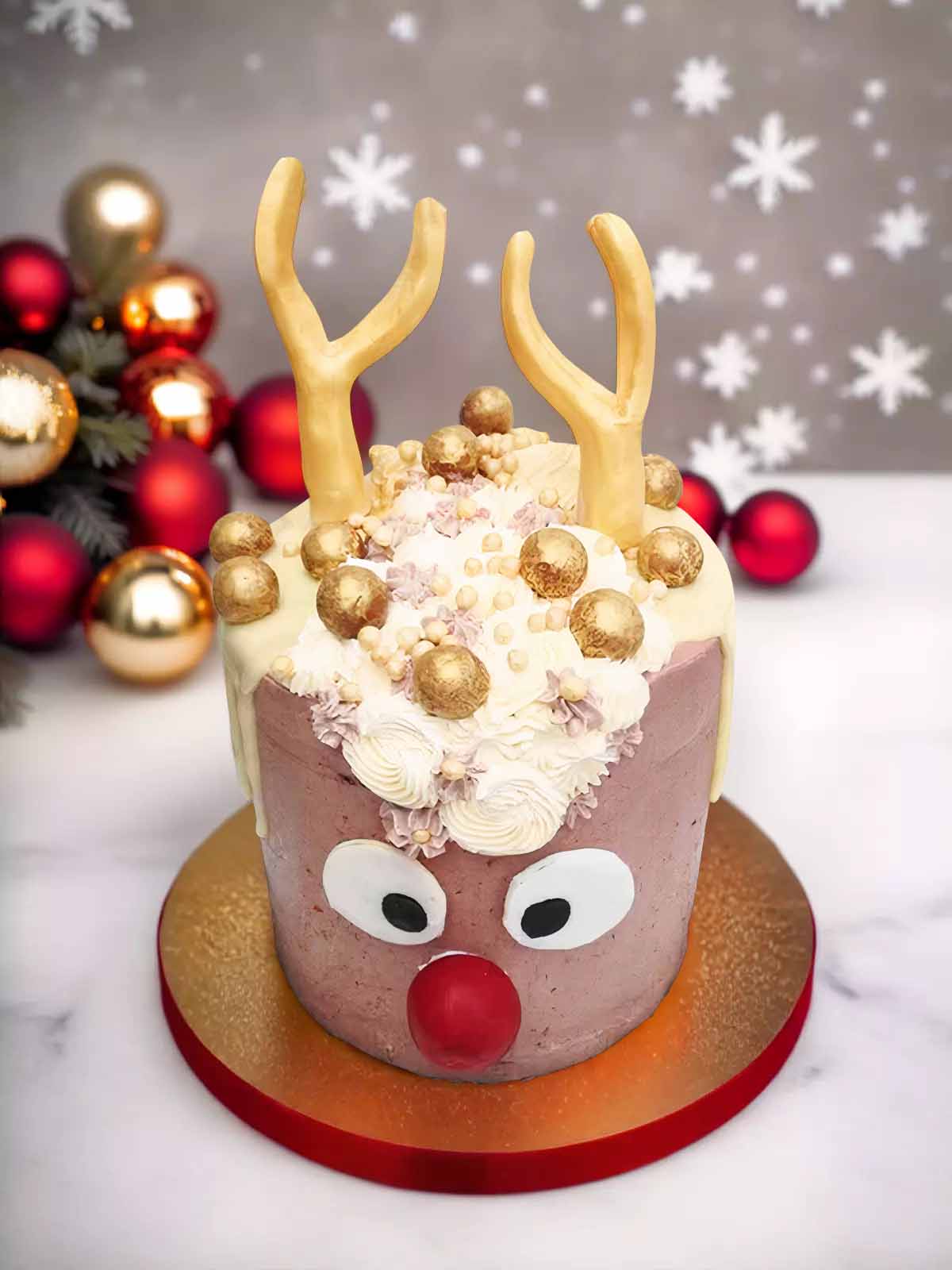 Rudolf cake with horns and red nose with golden balls.